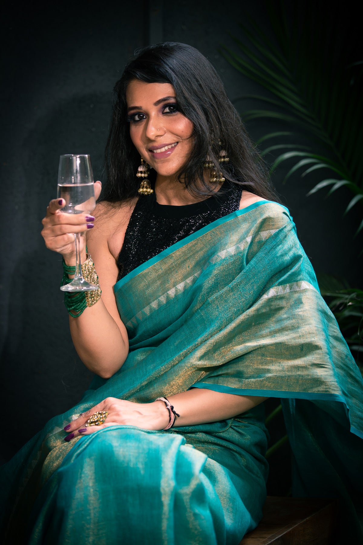 Model in Teal Green Premium Tissue Linen Saree holding a wine glass, exuding elegance and sophistication